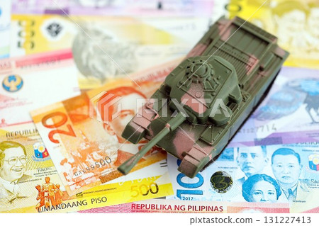 Philippines peso currency money bills and toy tank. The concept of army funds and weapons sales Philippines peso currency money bills and toy tank. The concept of army funds and weapons sales 131227413