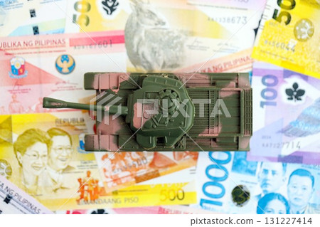 Philippines peso currency money bills and toy tank. The concept of army funds and weapons sales Philippines peso currency money bills and toy tank. The concept of army funds and weapons sales 131227414