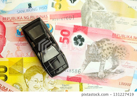 Philippines peso currency money bills and toy car. The concept of car ownership Philippines peso currency money bills and toy car. The concept of car ownership 131227419
