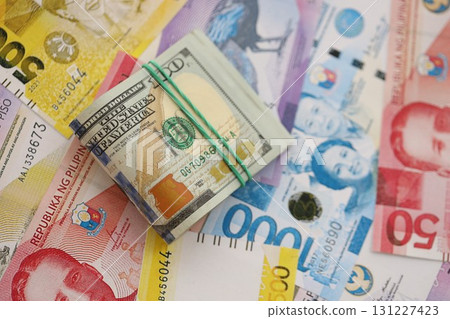 Philippines peso currency money bills and bunch of us dollar banknotes. The concept of economics and currency exchange Philippines peso currency money bills and bunch of us dollar banknotes. The concept of economics and currency exchange 131227423