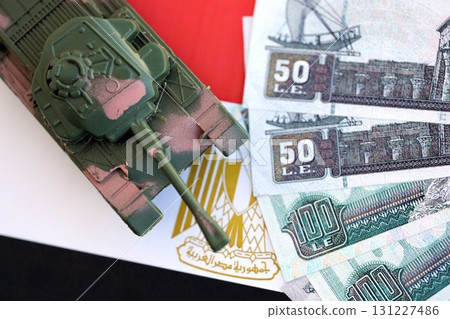 Egyptian pound currency money bills and toy tank on flag. The concept of army funds and weapons Egyptian pound currency money bills and toy tank on flag. The concept of army funds and weapons 131227486