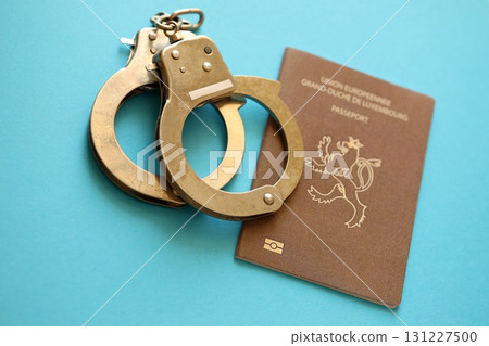 Luxembourg passport with police handcuffs on table. Criminal level and arrests in Europe Luxembourg passport with police handcuffs on table. Criminal level and arrests in Europe 131227500