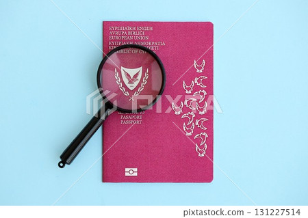 Kyprus passport and magnifying glass on light blue paper. Citizenship details and information 131227514