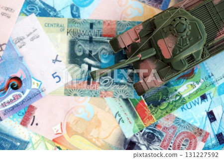 Kuwaiti dinar currency money bills and toy tank. The concept of army funds and weapons sales Kuwaiti dinar currency money bills and toy tank. The concept of army funds and weapons sales 131227592