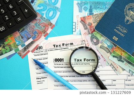 Kuwaiti dinar money bills and calculator with tax form on blue. Taxation and accounting concept Kuwaiti dinar money bills and calculator with tax form on blue. Taxation and accounting concept 131227609