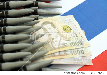 Thai baht currency money bills and rifle bullets on flag. Concept of warfare and gun selling 131227652