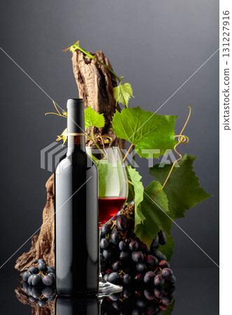Glass and bottle of red wine with blue grapes. Glass and bottle of red wine with blue grapes. 131227916