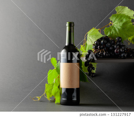 Bottle of red wine with blue grapes and vine branches. Bottle of red wine with blue grapes and vine branches. 131227917