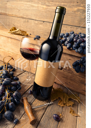 Bottle of red wine and blue grapes on a old wooden table. Bottle of red wine and blue grapes on a old wooden table. 131227930