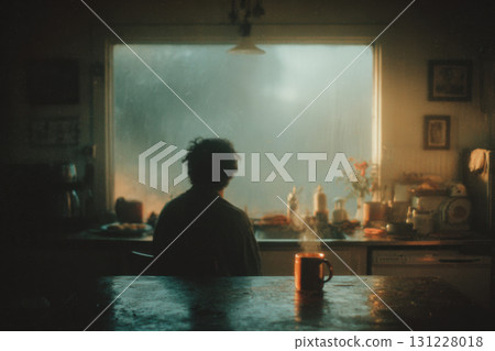 Seasonal depression. Person sits alone in dimly lit kitchen, gazing out foggy window, with steaming mug on table, evoking sense of solitude 131228018