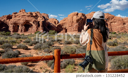 Female tourist capturing a view of Double Arch rock formation in Arches National Park, Utah, USA 131228452