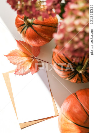 Blank greeting card and bright autumn leaf on white background, surrounded by pumpkins and flowers. Perfect for holidays and Thanksgiving 131228535