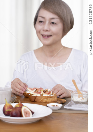Senior woman eating bread for breakfast out of focus Senior woman eating bread for breakfast out of focus 131228786