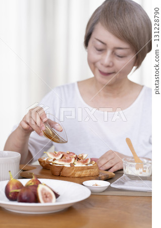 Senior woman eating bread for breakfast out of focus 131228790