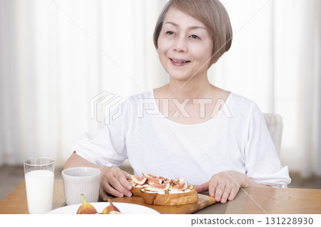 Senior woman eating bread for breakfast 131228930