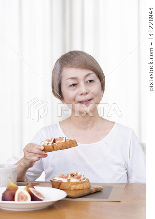 Senior woman eating bread for breakfast Senior woman eating bread for breakfast 131228943