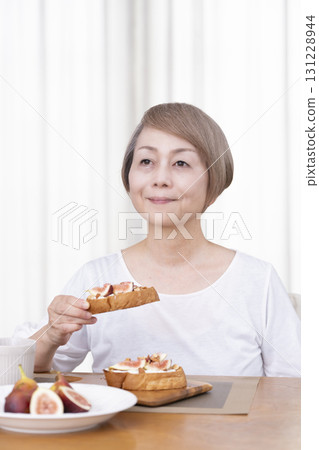 Senior woman eating bread for breakfast Senior woman eating bread for breakfast 131228944