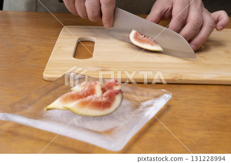 Cutting freshly picked figs, a taste of autumn, with a knife Cutting freshly picked figs, a taste of autumn, with a knife 131228994