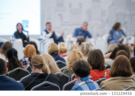 Diverse audience attends panel discussion at conference with speakers on stage and engaged attendees Diverse audience attends panel discussion at conference with speakers on stage and engaged attendees 131229438