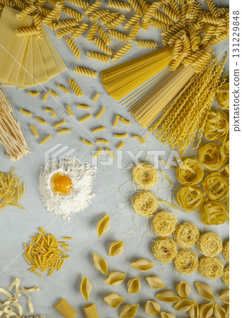 Various types of italian pasta forming a circle around flour and egg yolk 131229848