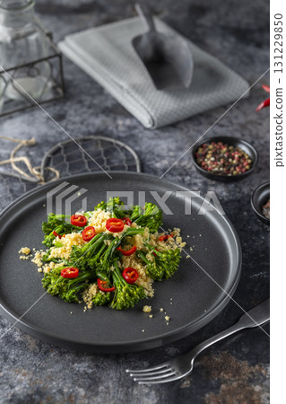 Delicious broccolini salad with toasted breadcrumbs and chili pepper flakes on black plate 131229850