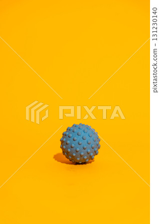 Blue spiky massage ball on bright orange minimal fitness recovery concept with copy space 131230140