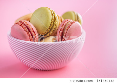 Different flavors of macarons. Colourful macaroons in bowl on pink background. 131230438
