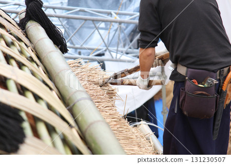 A man trimming a thatched roof A man trimming a thatched roof 131230507