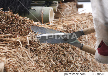 A man trimming a thatched roof A man trimming a thatched roof 131230508