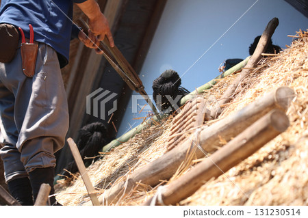 A man trimming a thatched roof A man trimming a thatched roof 131230514
