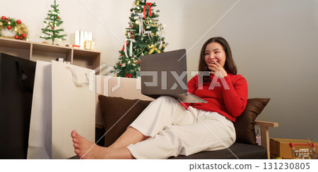 Happy woman enjoying online shopping during Christmas season 131230805