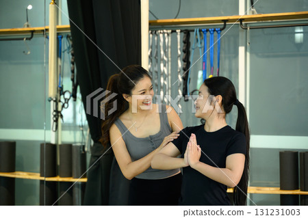 Female yoga instructor assisting student in a twisting prayer pose during indoor training session 131231003