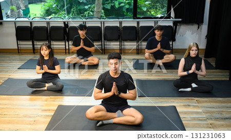 People in meditation posture during group yoga session, focusing on relaxation and balance 131231063