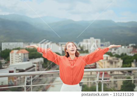 Cheerful businesswoman celebrating success outdoors, smiling with open arms against mountain and city skyline Cheerful businesswoman celebrating success outdoors, smiling with open arms against mountain and city skyline 131231120
