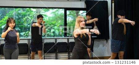 Group fitness class practicing boxing moves with focus and energy indoors 131231146