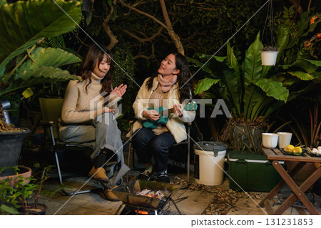 Winter camp outdoor friend people forest woman happy, playing ukulele and enjoying warm campfire, sharing laughter during relaxing cozy winter evening leisure getaway. 131231853