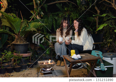 Winter camp outdoor adventure, happy women friends gather in forest, sharing warm drinks near fire during cozy winter evening, building joyful memories. Winter camp outdoor adventure, happy women friends gather in forest, sharing warm drinks near fire during cozy winter evening, building joyful memories. 131231890