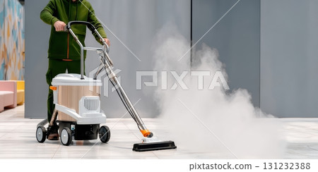 A person operates a steam cleaner, efficiently cleaning a floor, emitting steam 131232388
