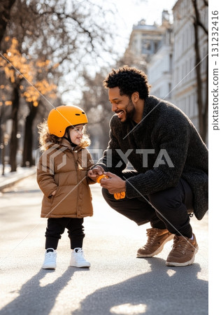 A happy father helps his toddler daughter put on her safety helmet before a bike ride A happy father helps his toddler daughter put on her safety helmet before a bike ride 131232416