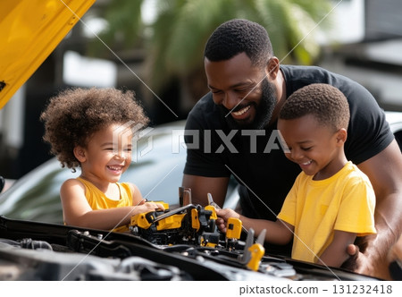 Happy Black father and his two children playing with toy cars near the open hood of a yellow car Happy Black father and his two children playing with toy cars near the open hood of a yellow car 131232418