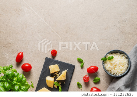 Parmesan cheese, cherry tomatoes and fresh basil on a slate board on a light background. 131232623