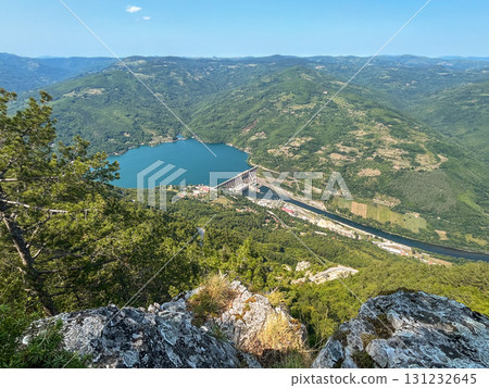Scenic aerial view of hydroelectric dam on turquoise lake surrounded by lush green forest 131232645