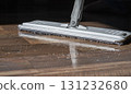 Close-up of a mop cleaning a wooden floor with water and detergent 131232680