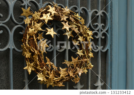 Golden christmas wreath made of stars on a iron metal door Golden christmas wreath made of stars on a iron metal door 131233412