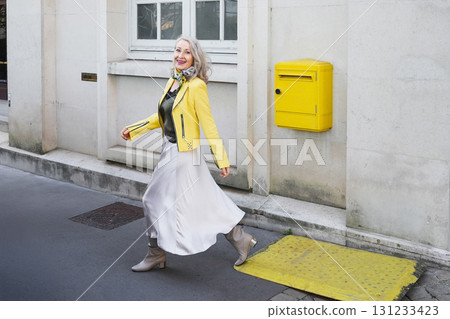 Attractive gray-haired woman in her sixties in a yellow jacket 131233423