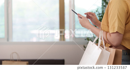 Online Shopping. Checking smartphone while holding shopping bags. 131233587