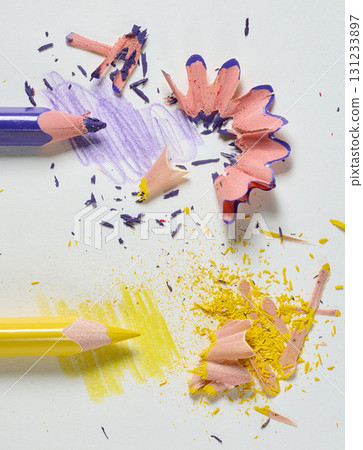Purple and yellow pencils with colored shavings and drawn strokes on white sheet of paper, close-up Purple and yellow pencils with colored shavings and drawn strokes on white sheet of paper, close-up 131233897