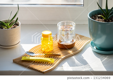 Bottle of fish oil capsules, glass of water and spoon on wooden board. Bottle of fish oil capsules, glass of water and spoon on wooden board. 131234069