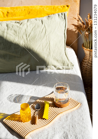 Glass of water with vitamin supplements on bed. Morning routine for health and wellness. Glass of water with vitamin supplements on bed. Morning routine for health and wellness. 131234079