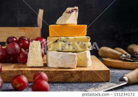 Different types of cheese on a board, served with grapes and dried fruits. Different types of cheese on a board, served with grapes and dried fruits. 131234172